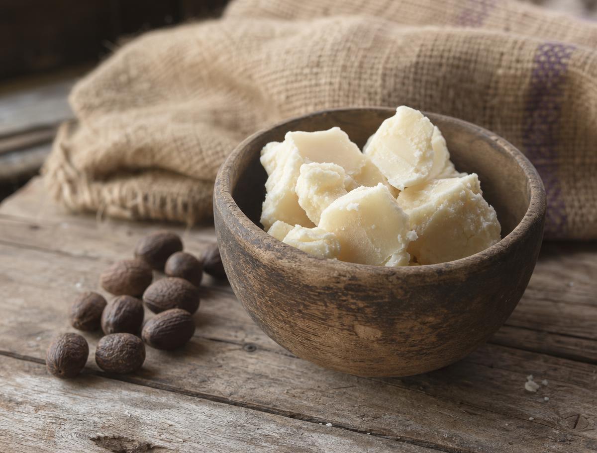 Wooden bowl of unrefined Ghanaian shea butter with shea nuts